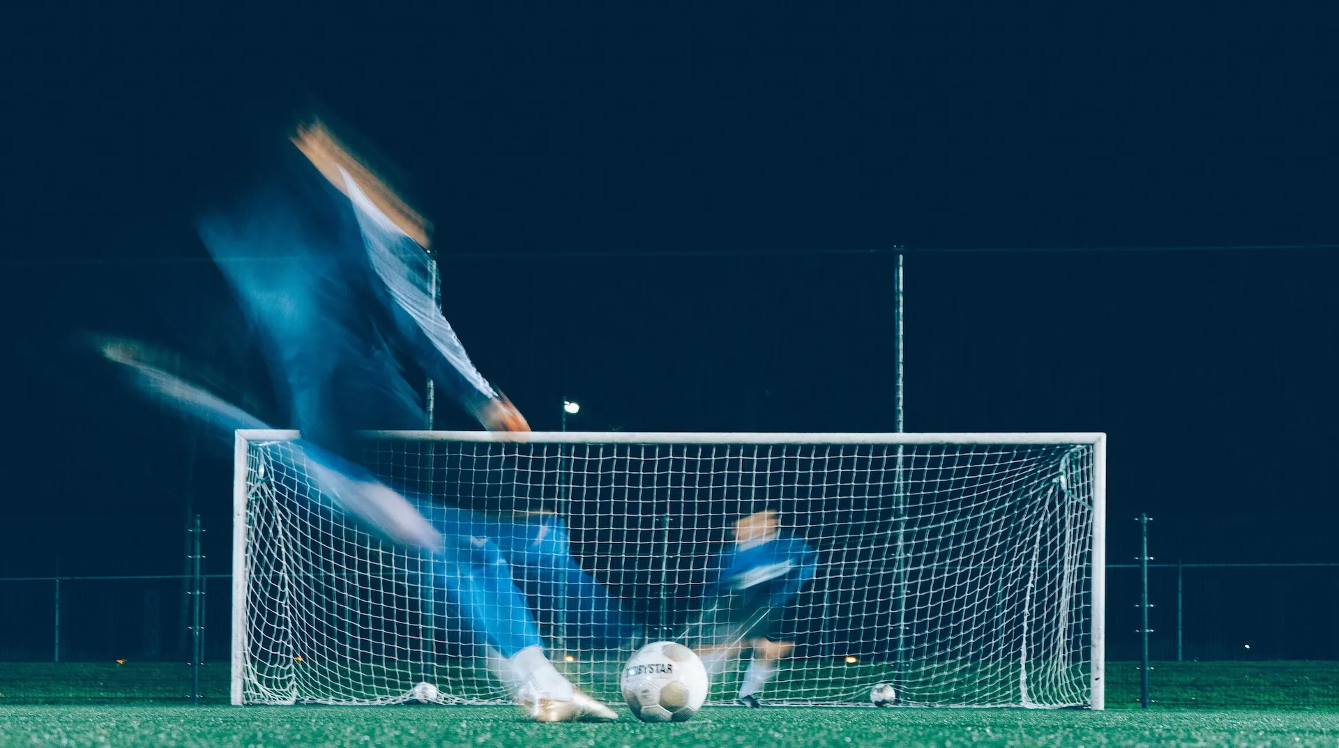 Ein Bild eines Fußballspielers, der im Sprung den Ball vor dem Tor trifft, als Symbolbild für die Kategorie Sport.